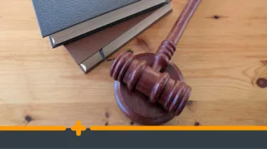 Drewniany młotek sędziowski i książki prawnicze na biurku