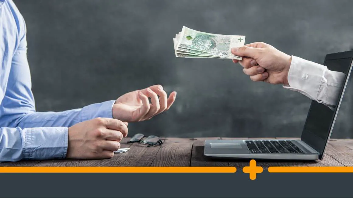 Ręka wręczająca gotówkę z laptopa drugiej osobie