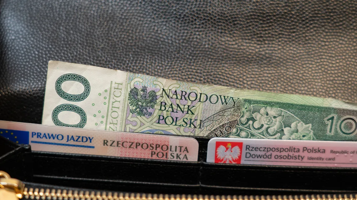 Portfel z banknotem 100 zł i dokumentami: dowód osobisty oraz prawo jazdy